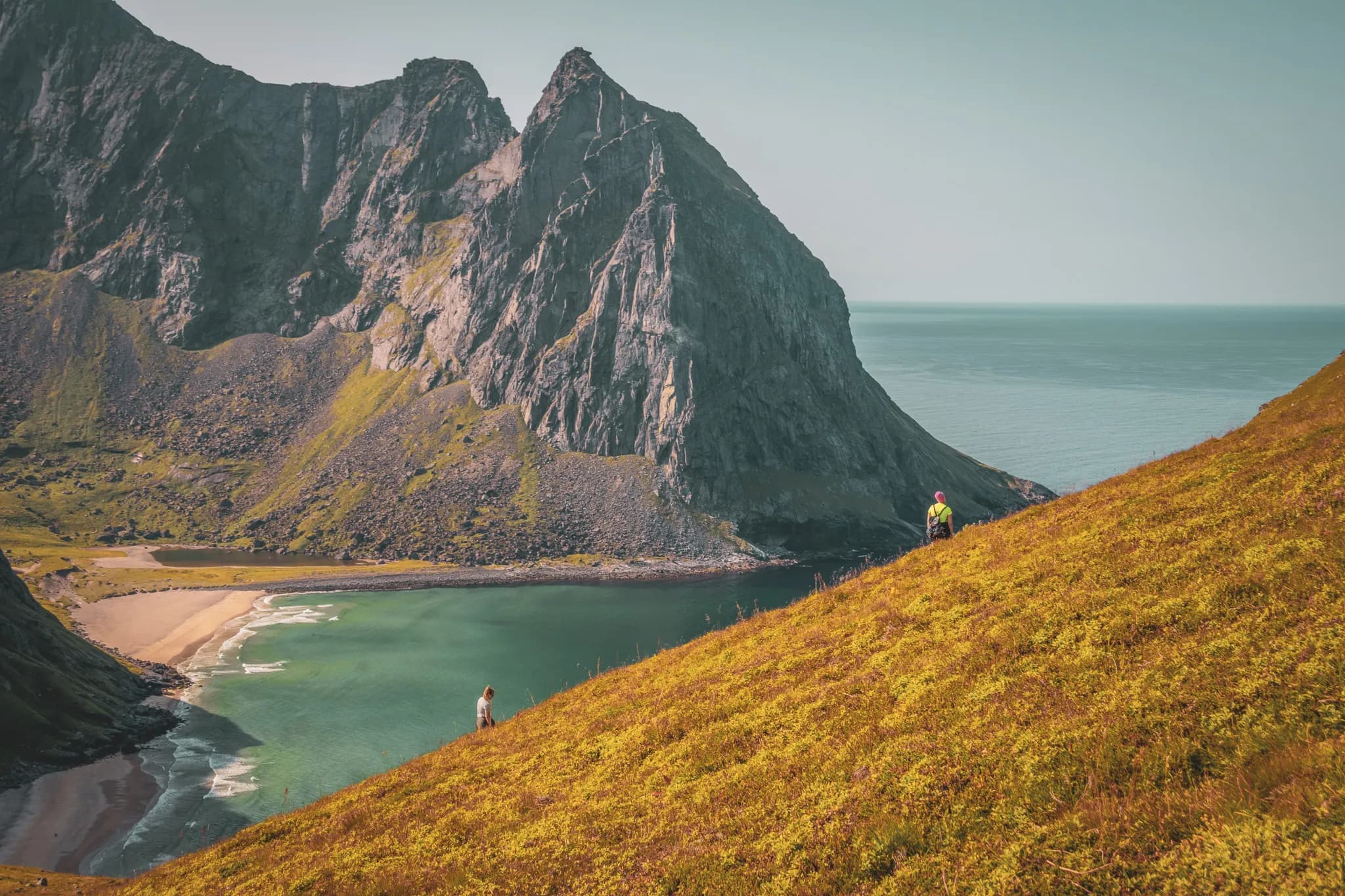 Hikers exploring the majestic landscapes of the Lofoten Islands, between mountains and turquoise sea.