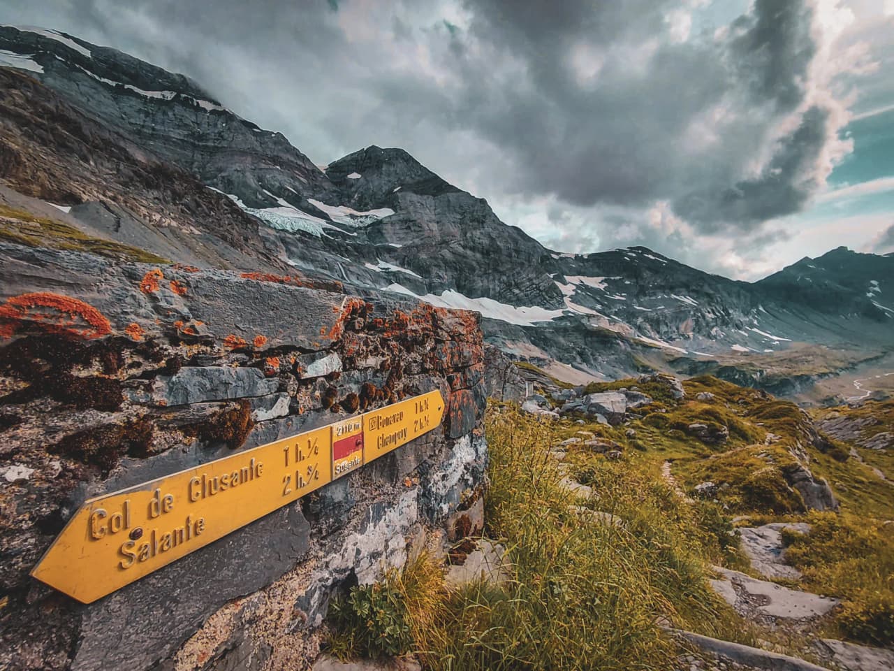 A signpost in the heart of the Alps, surrounded by majestic green landscapes.