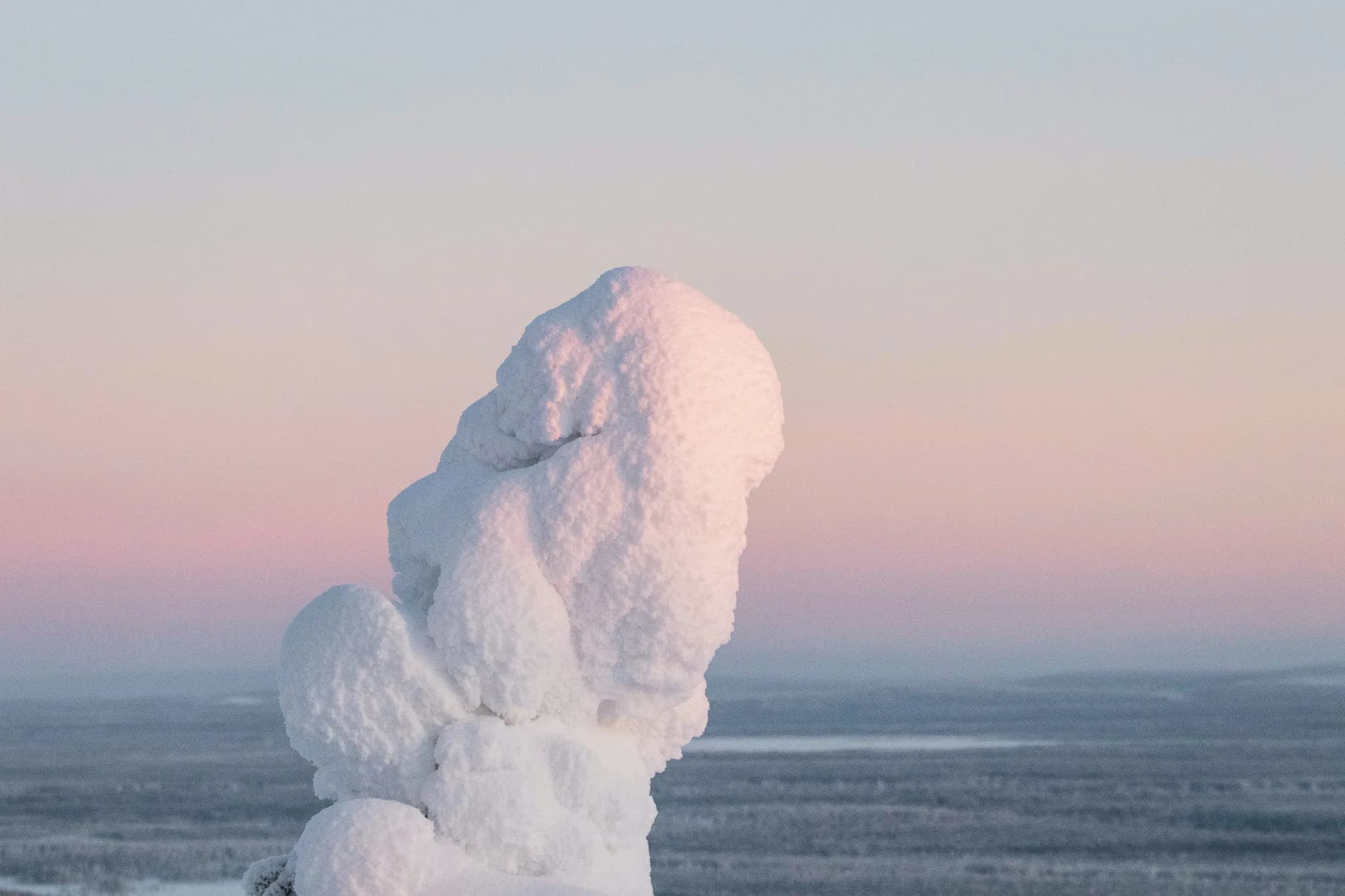 Pigne de neige majestueuse sous un ciel pastel, invitant à l'évasion en Laponie.
