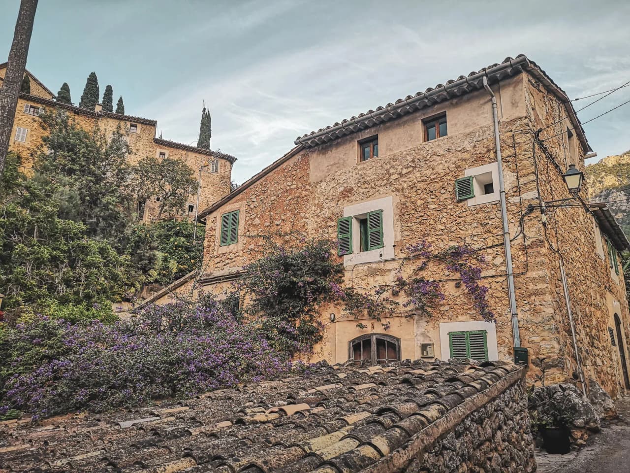 Charmante maison en pierre à Majorque, entourée de verdure et de fleurs violettes. Évasion garantie !