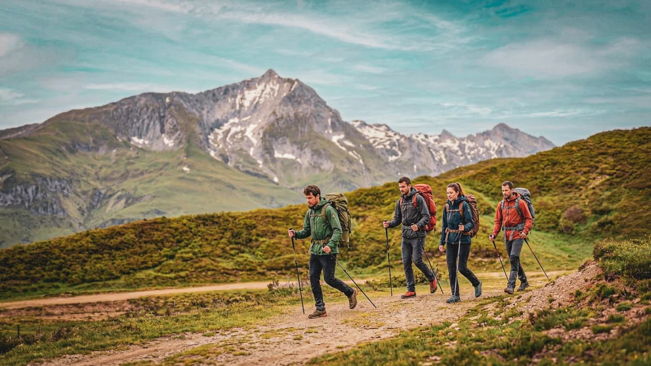 Groupe de randonneurs sur un sentier des Pyrénées, entouré de paysages montagneux majestueux.