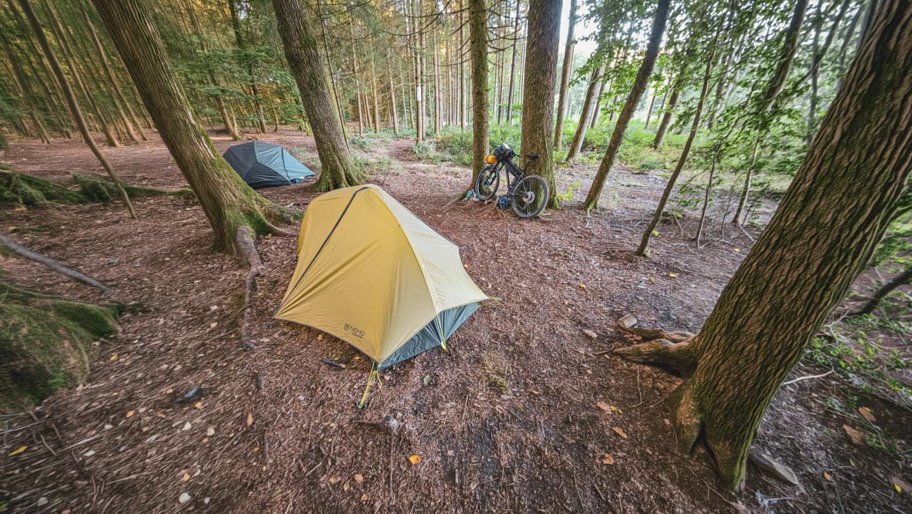 Colourful tents and bicycles in a peaceful forest, ideal for a wild bivouac.