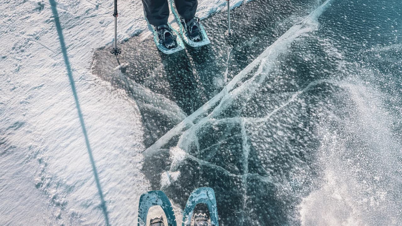Snowshoes on a frozen lake, surrounded by glistening ice and snow, inviting adventure.