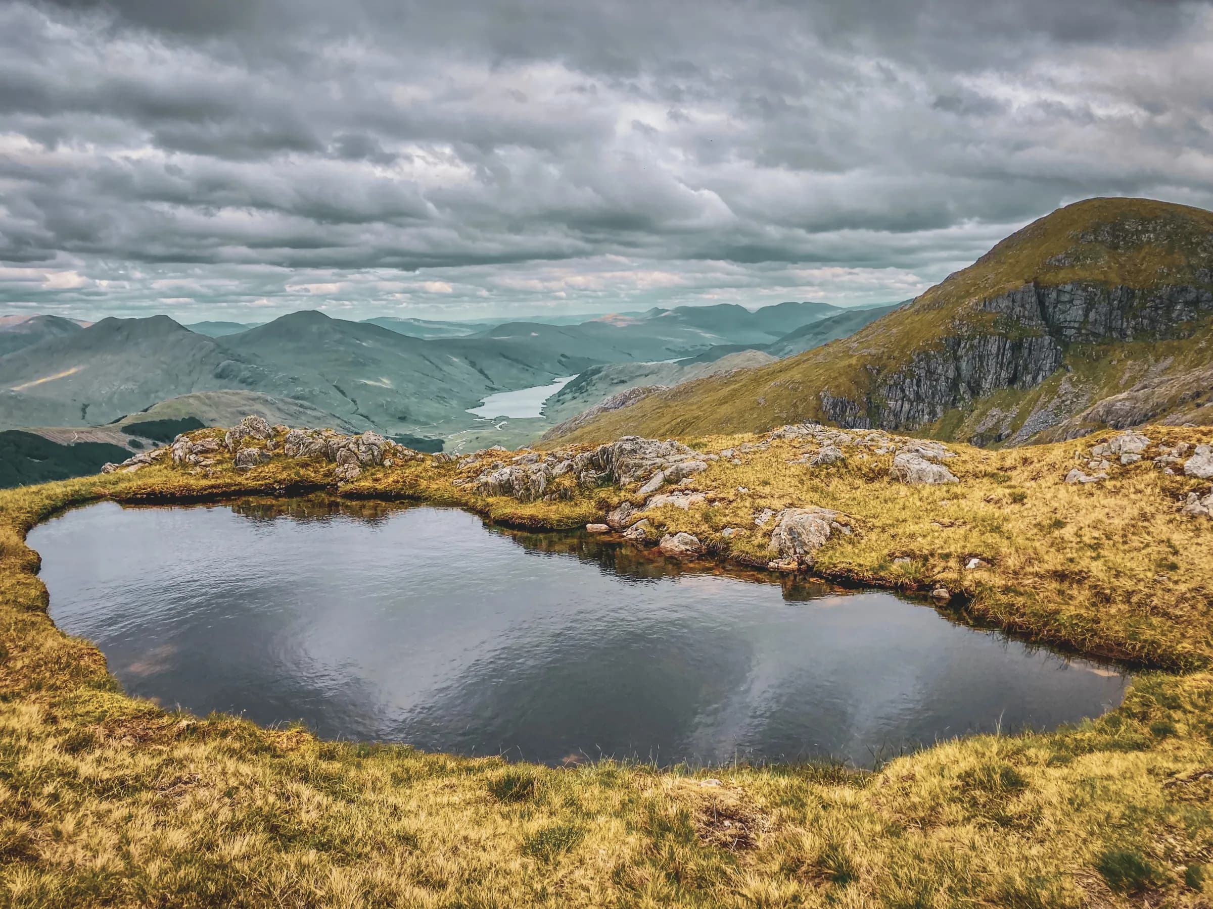 Majestic views of the Scottish Highlands, with a peaceful lake and verdant mountains.