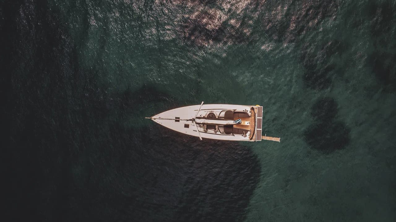 Un voilier naviguant sur des eaux turquoise, entouré de paysages méditerranéens enchanteurs.