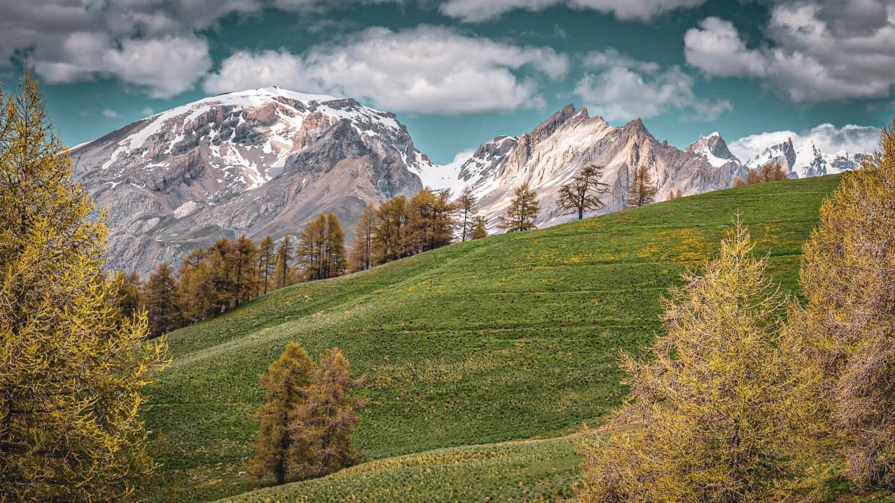 Montagnes majestueuses et vallées verdoyantes sous un ciel nuageux, invitation à l'aventure.