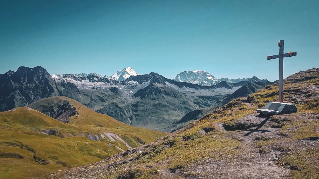 Een majestueus panorama van de Alpen met een kruis, dat uitnodigt om op avontuur te gaan rond de Mont Blanc.