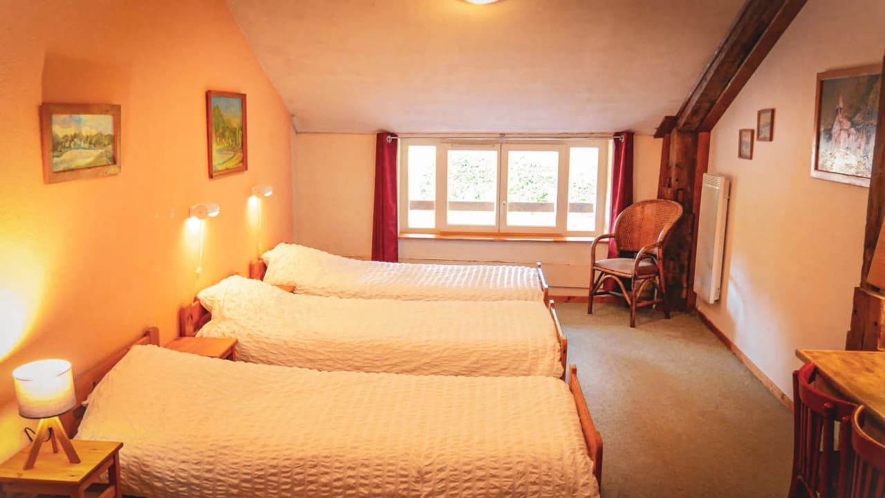 A cosy room with twin beds, rustic decor and views of nature, perfect for a soothing stay.