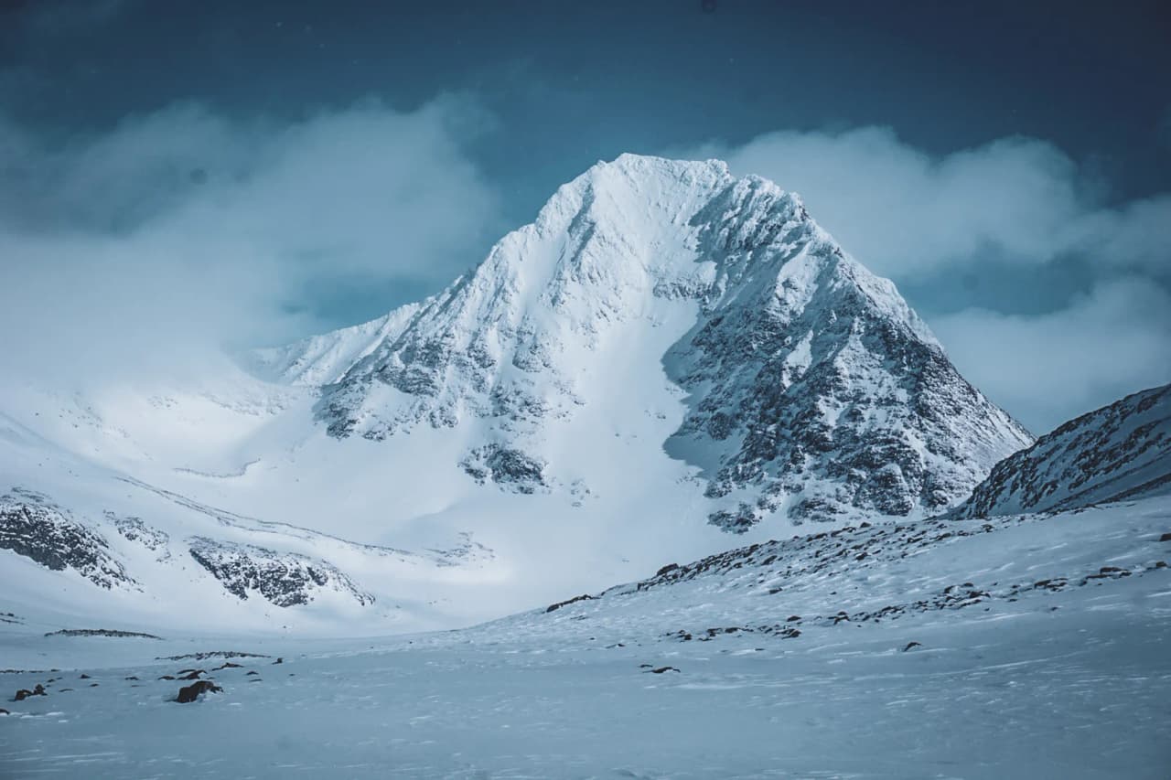 Een majestueuze besneeuwde top onder een blauwe hemel, een belofte van avontuur in Lapland.