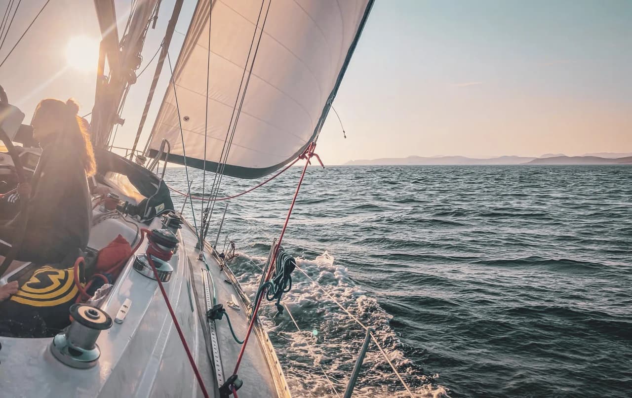 A ship at sea under a clear sky, sails billowing in the wind, a peaceful moment of escape.