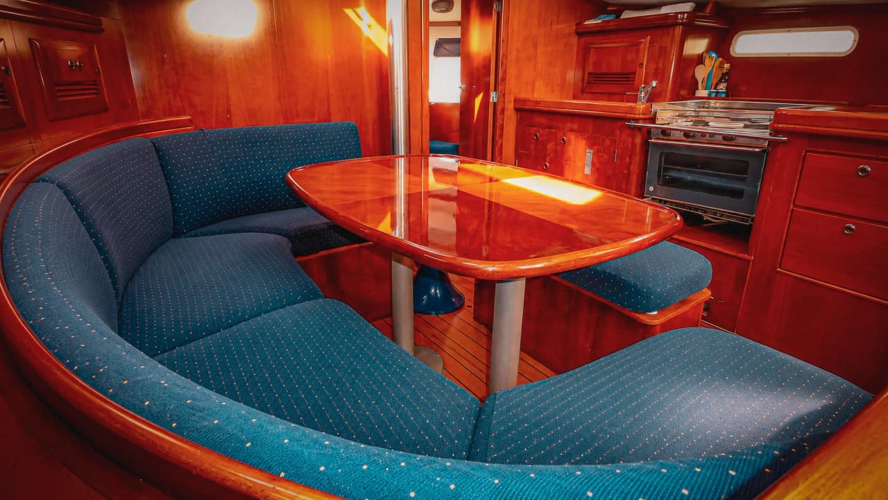 Het warme interieur van een zeiljacht, met een gezellige eethoek en een maritieme sfeer.