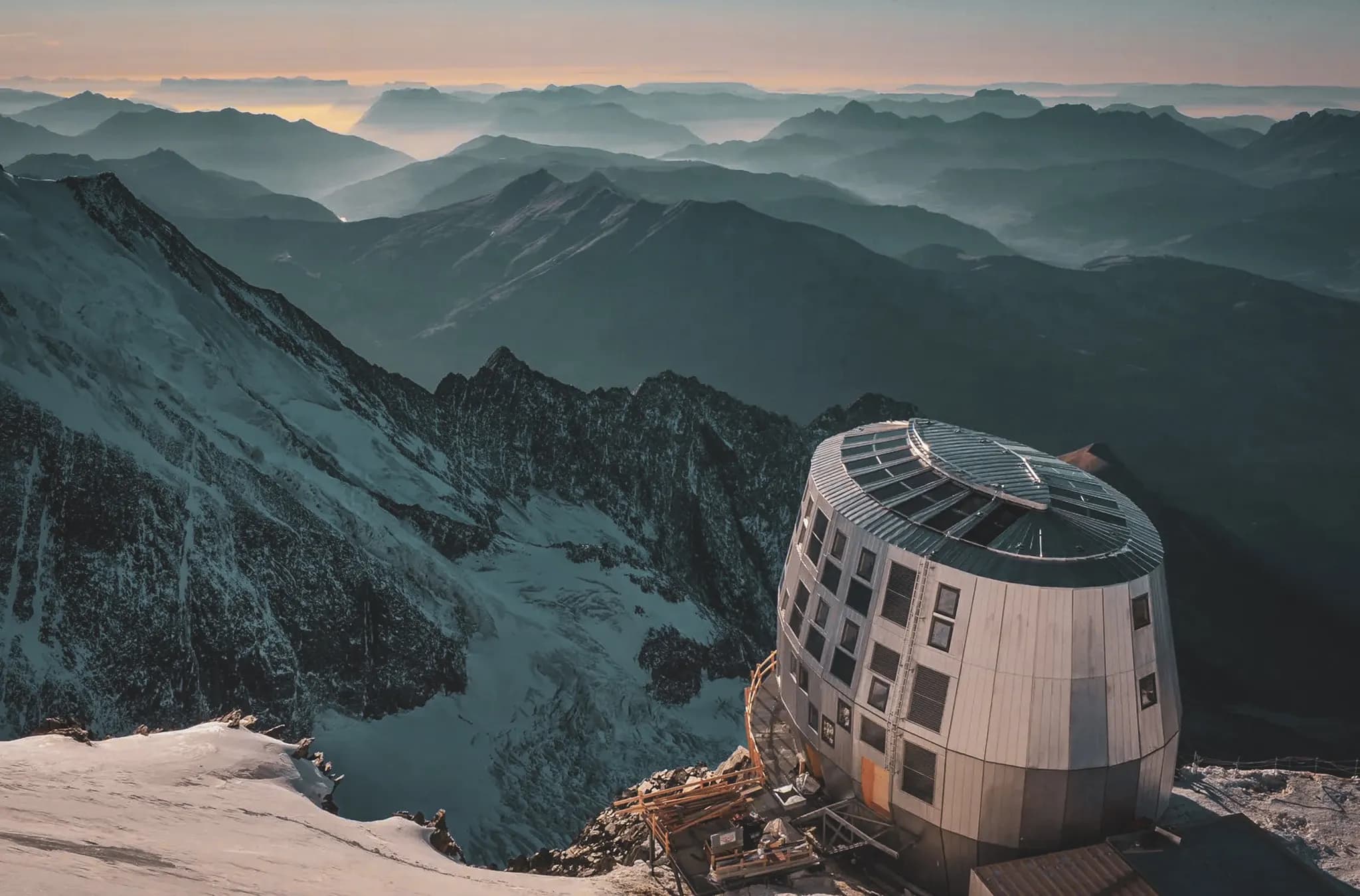 Vue imprenable sur les sommets alpins, avec un refuge moderne surplombant les vallées majestueuses.