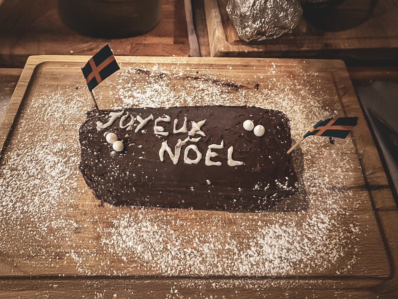 Gâteau au chocolat festif "Joyeux Noël" décoré de drapeaux suédois, sur un plateau en bois.