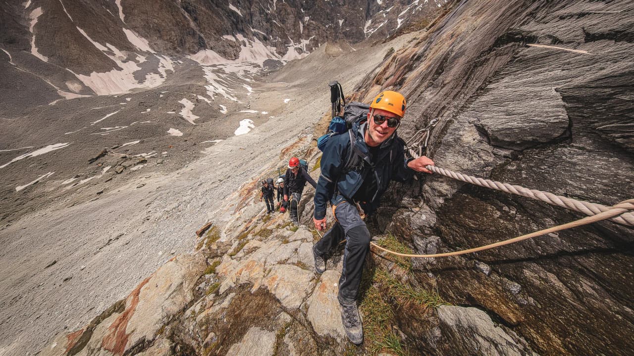 Hikers scale majestic glacial cliffs in the midst of an alpine adventure.