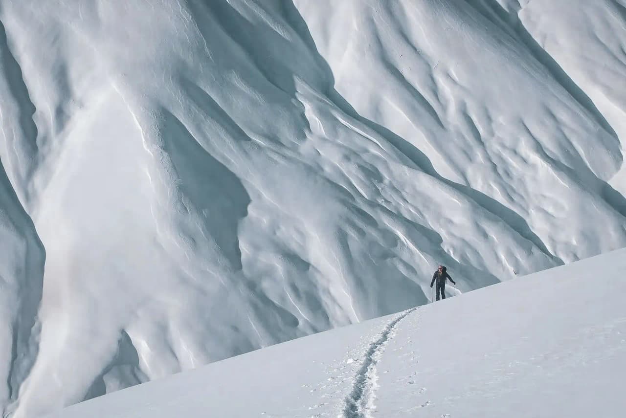 Ski de randonnée sur une pente vierge, avec des sommets enneigés en arrière-plan, invitation à l’aventure.