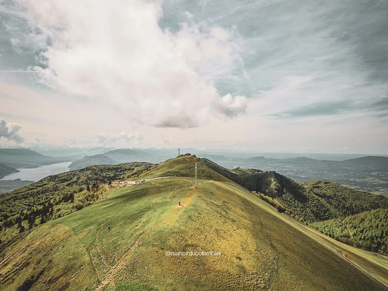 Panoramic view from the summit of Grand Colombier, with greenery, sparkling lake and surrounding mountains.