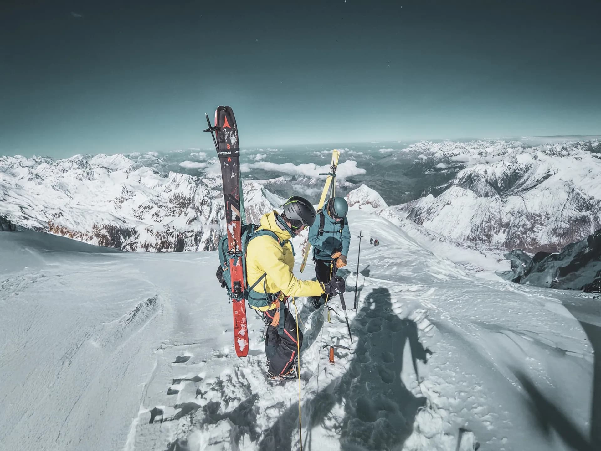 Twee skiërs wandelen op de Mont Blanc, omringd door besneeuwde Alpenlandschappen.