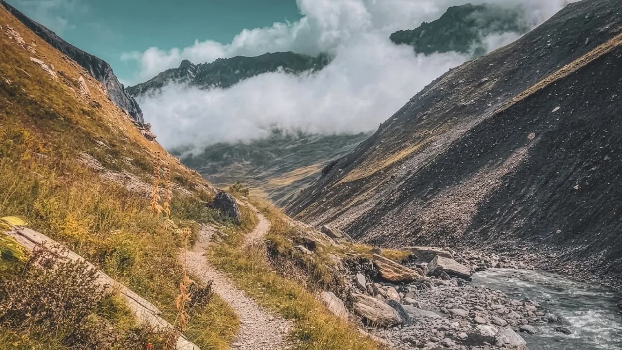 Sentier enchanteur au cœur des montagnes, entre nuages et rivières cristallines. Aventure alpine !
