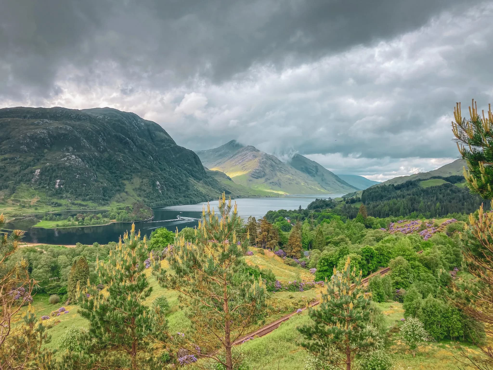 Majestueuze uitzichten op de Highlands, tussen groene bergen en sprankelende lochs, onder een bewolkte hemel.