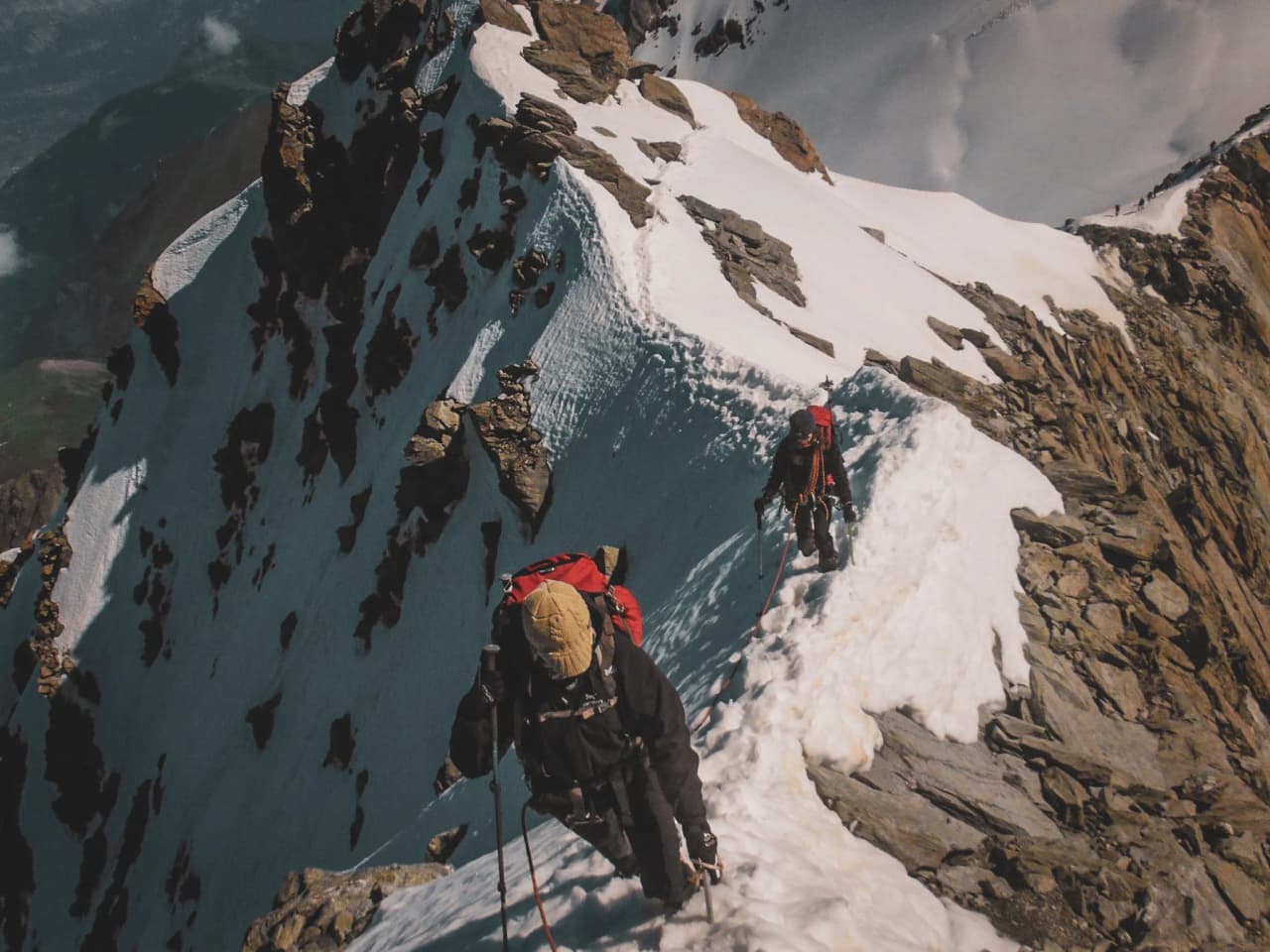 Bergbeklimmers steken een besneeuwde top over met uitzicht op een adembenemend panoramisch uitzicht op de gletsjers.