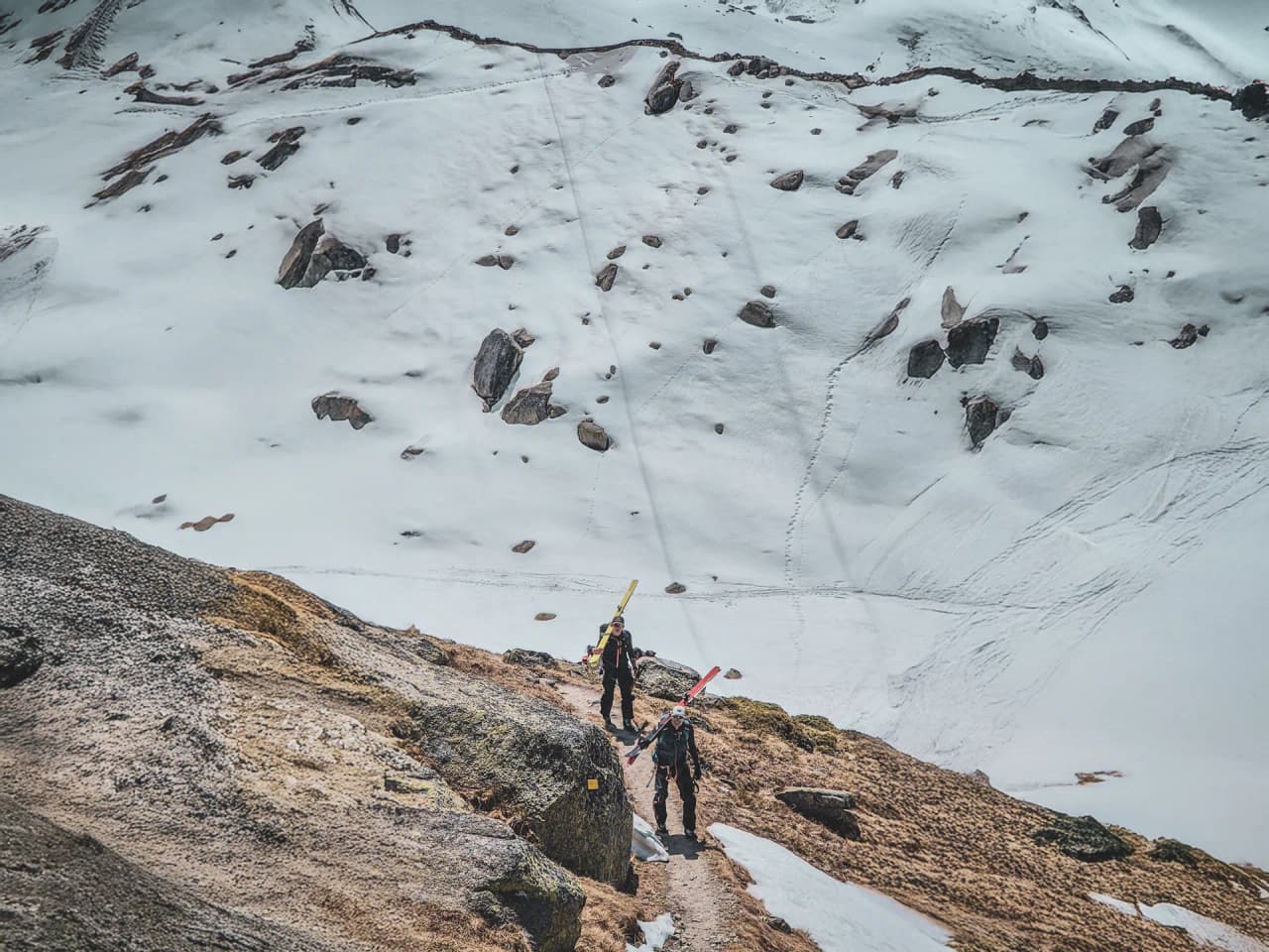 Deux randonneurs en ski traversent un paysage montagneux enneigé, prêts pour l'ascension du Mont Blanc.