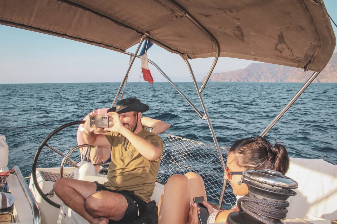 Un groupe sur un voilier en Corse, capturant des souvenirs avec la mer en toile de fond.