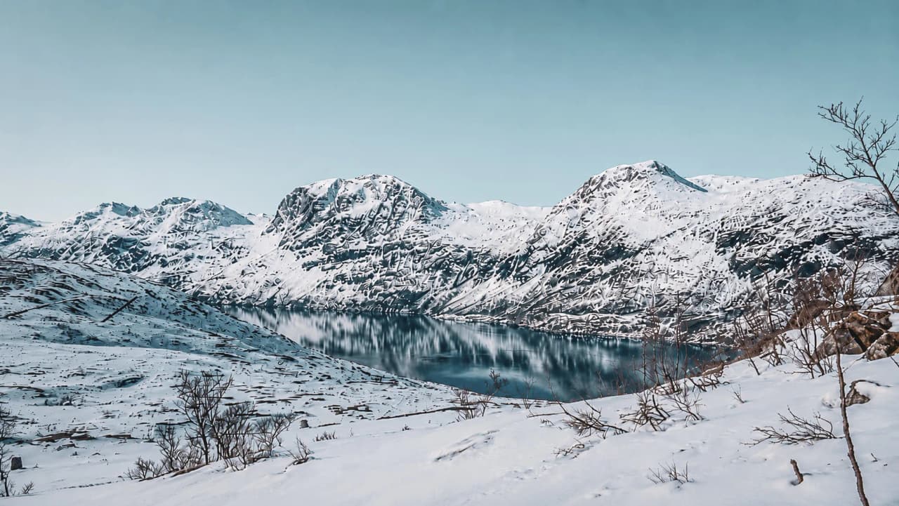 Een adembenemend sneeuwlandschap met majestueuze bergen en een vredig meer in Tromsø.