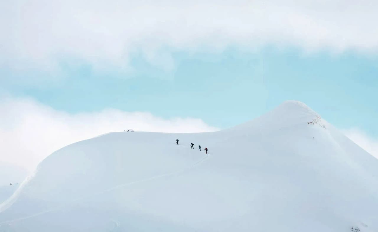 A group of skiers on a snowy slope, under a soothing blue sky.