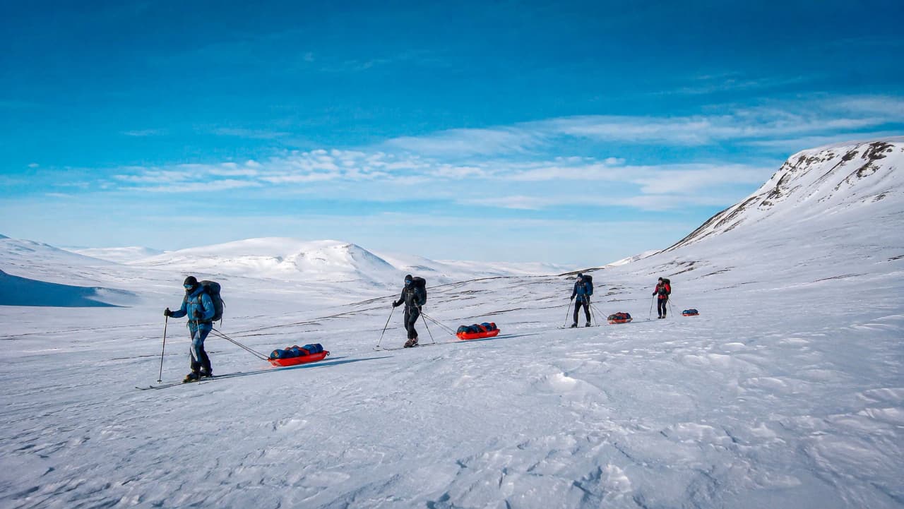 Winterreis: langlaufers die pulka’s voorttrekken op de Kungsleden, prachtige besneeuwde landschappen.