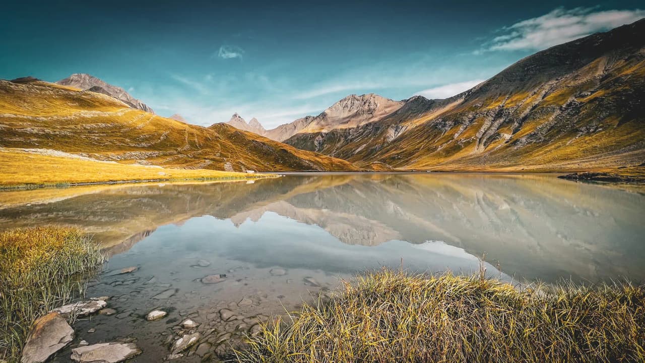 Lac paisible entouré de montagnes majestueuses au cœur des Alpes, reflet enchanteur.