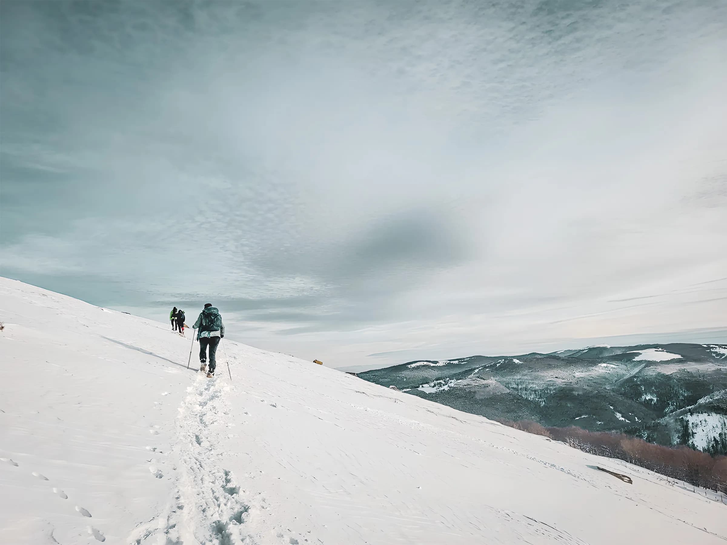 Sentier enneigé dans les Vosges, des randonneurs profitent d'un paysage majestueux.