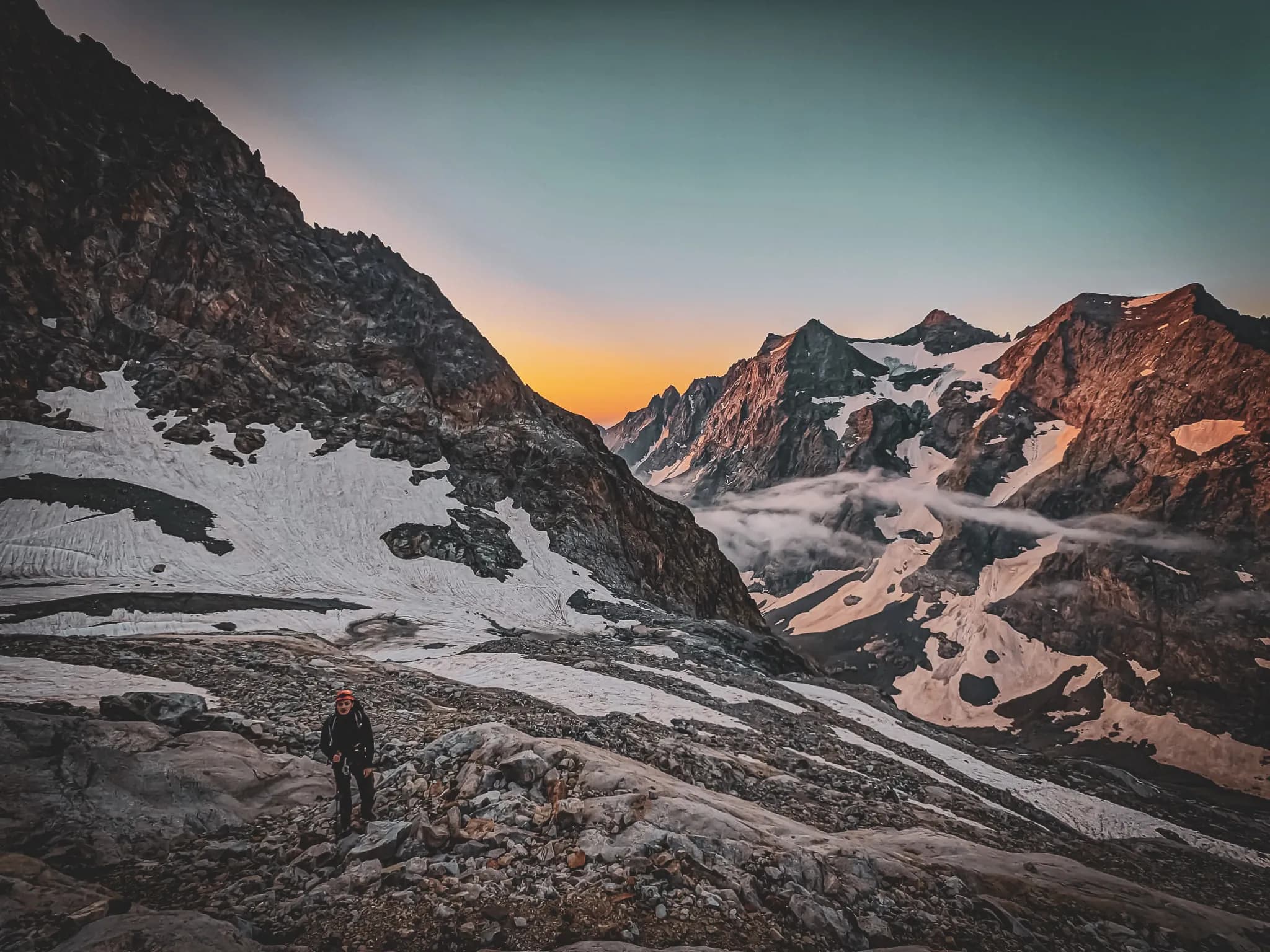 Randonneur dans les Ecrins, entre sommets majestueux et paysages enchanteurs au lever du soleil.