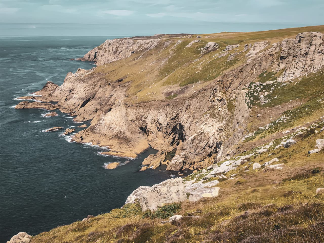 Falaises côtières spectaculaires surplombant une mer sereine, invitant à l'exploration maritime.