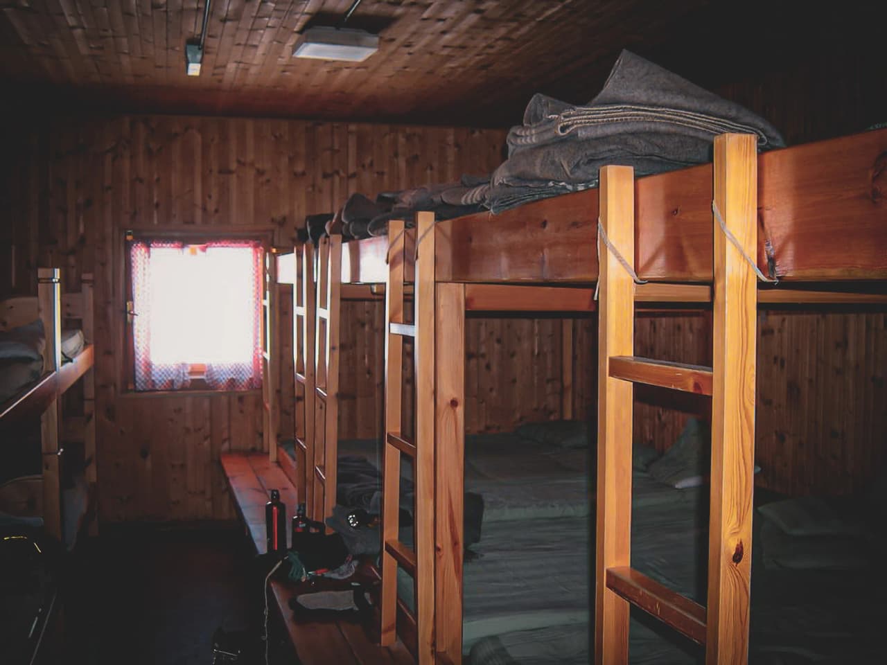 Cabane en bois chaleureuse avec lits superposés, offrant une vue sur les Alpes majestueuses.
