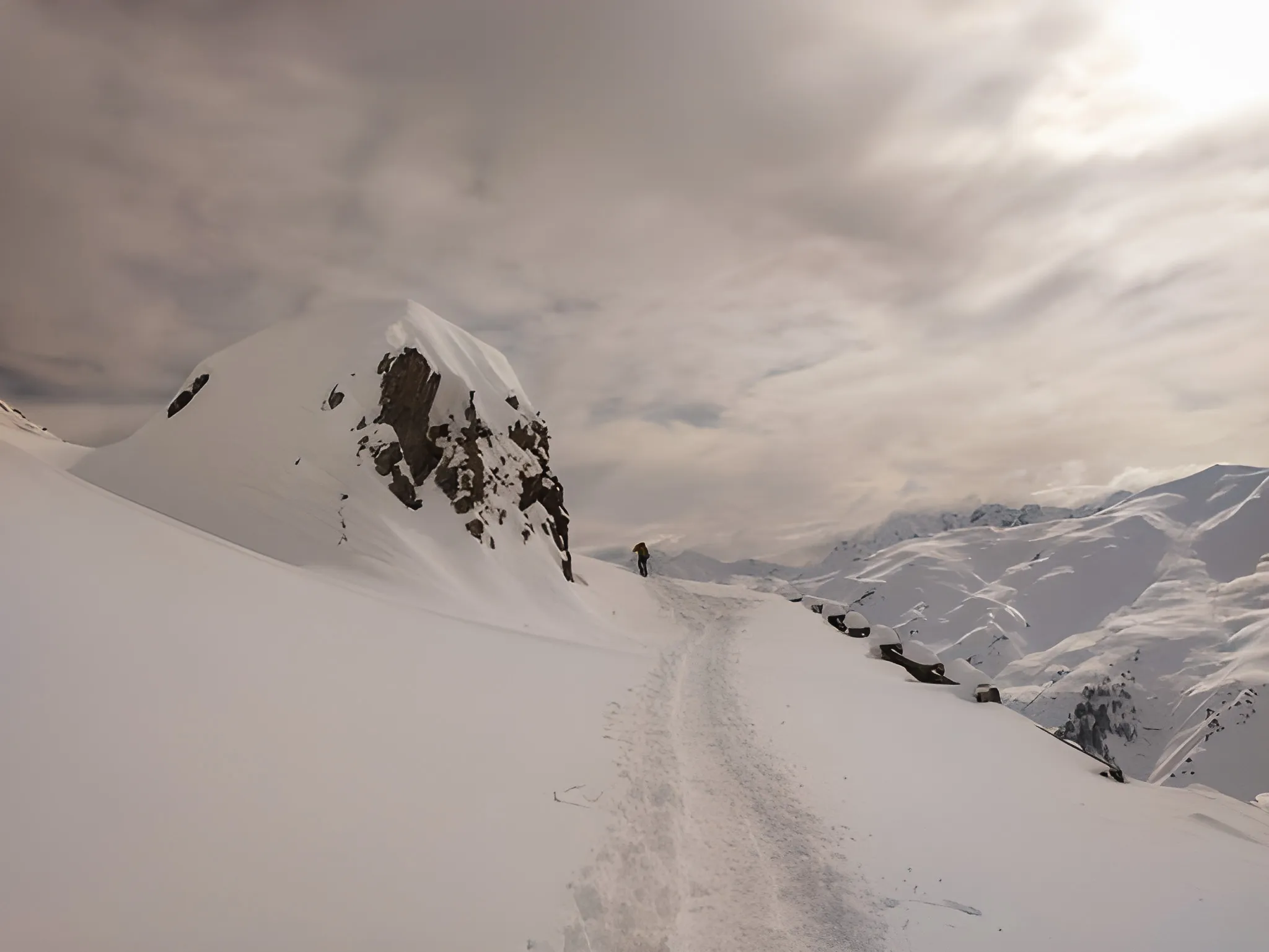 Een besneeuwd pad slingert langs majestueuze bergtoppen en nodigt je uit voor een winters avontuur.