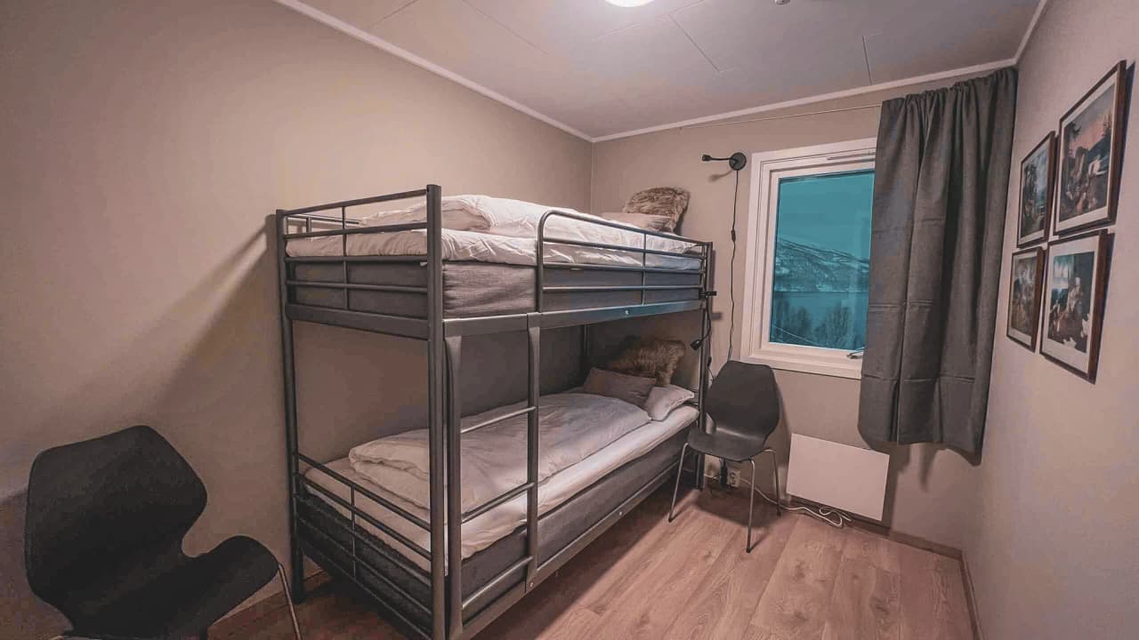 Gezellige kamer met stapelbedden en een raam met uitzicht op de Noorse bergen.