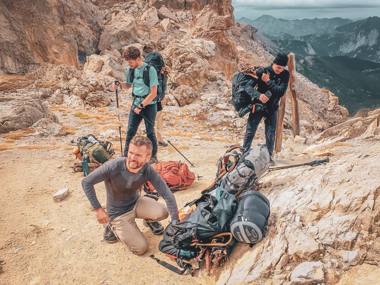 Trois aventuriers se préparent en haute montagne, entourés de paysages alpins impressionnants.