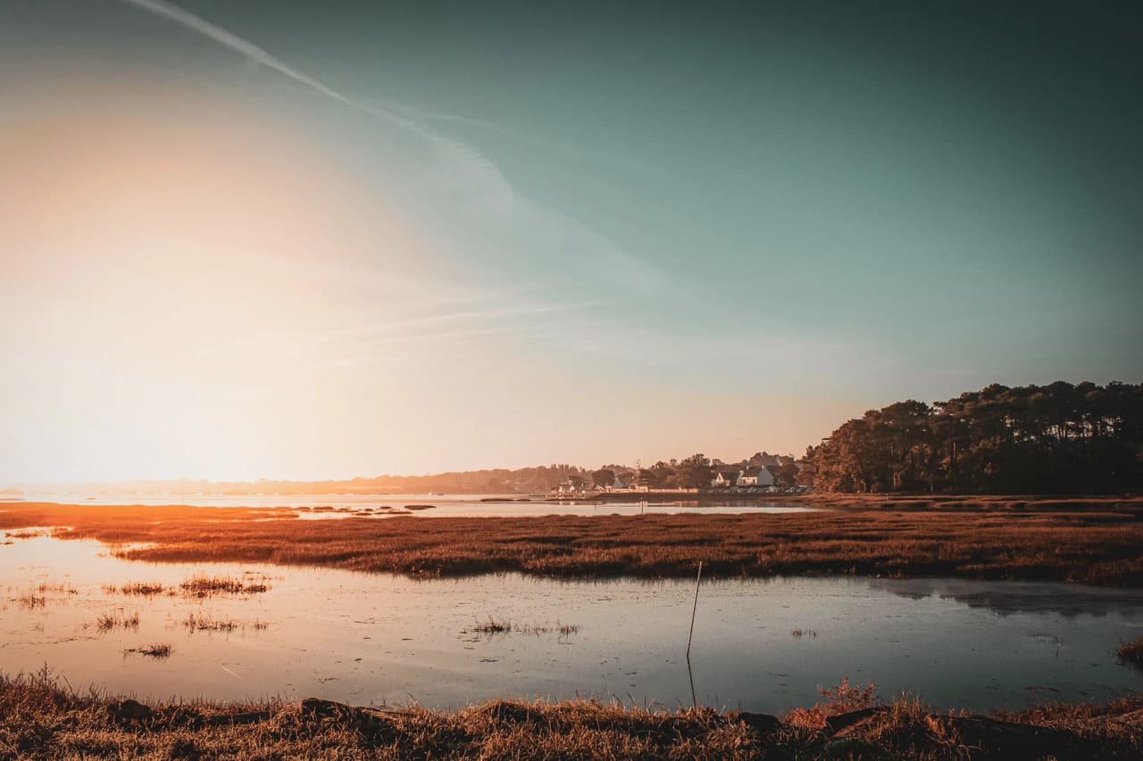 Coucher de soleil sur les marais, reflet paisible, invitant à l'évasion en Bretagne.