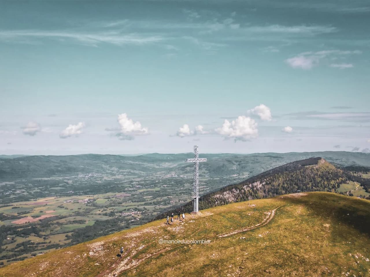 Panoramic view of the Grand Colombier, with a majestic cross, inviting you to take part in an adventure in the heart of nature.