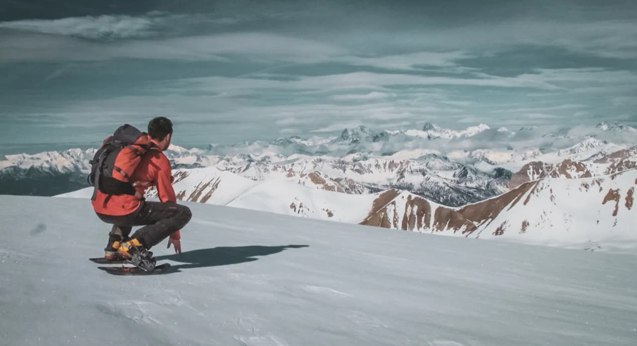 Snowshoe trekking on a snow-covered summit, admiring majestic Alpine scenery.