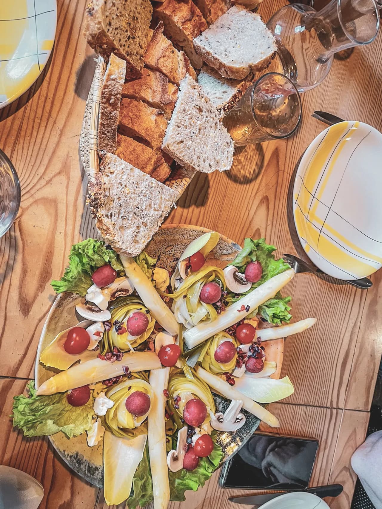 A colourful dish with salad, tomatoes and fresh bread on a wooden table, inviting you to explore.