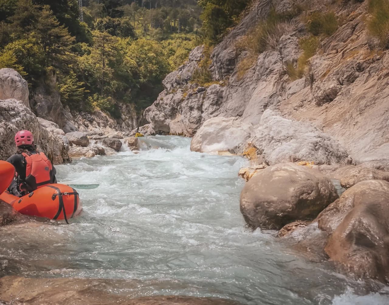 A packraft adventure in the turquoise waters of Slovenia's alpine rivers, surrounded by rocks.