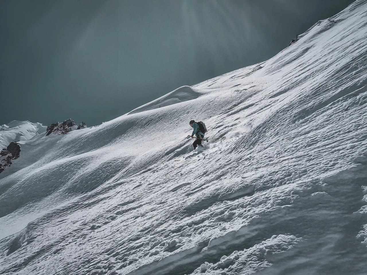 Un skieur s'aventure sur des pentes enneigées, avec le Mont Blanc en toile de fond majestueuse.