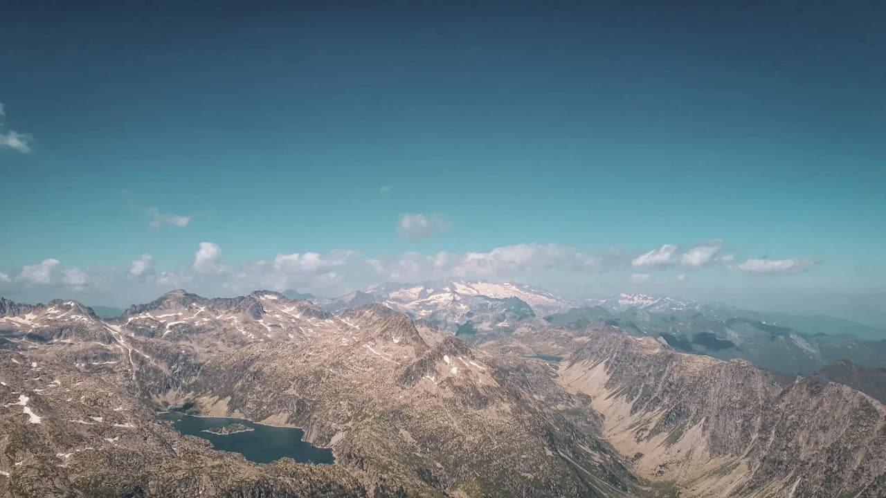 Panoramic views of the majestic Encantats mountains and sparkling lakes under a blue sky.