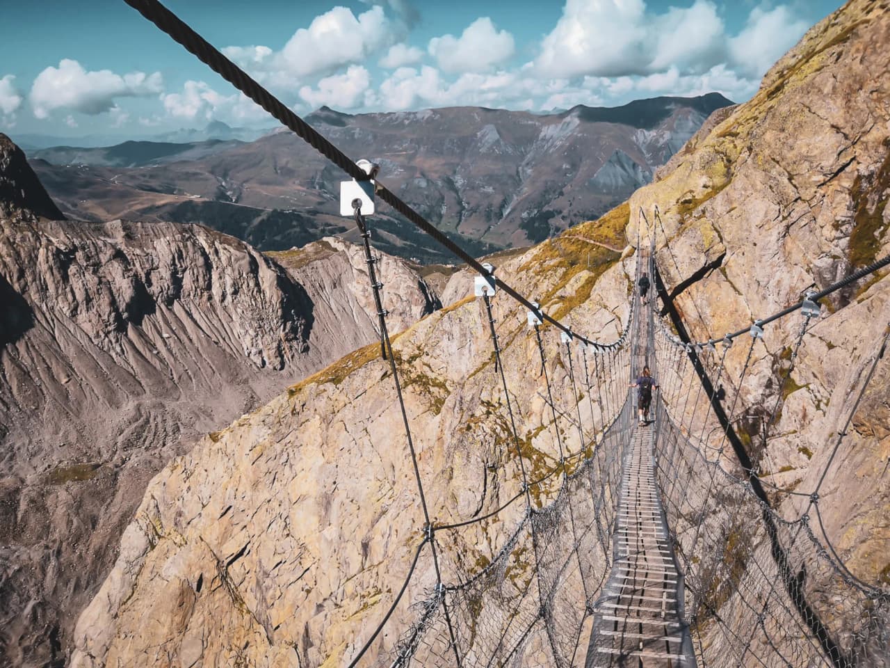 Een hangbrug met uitzicht op majestueuze bergen, een uitnodiging tot alpien avontuur.