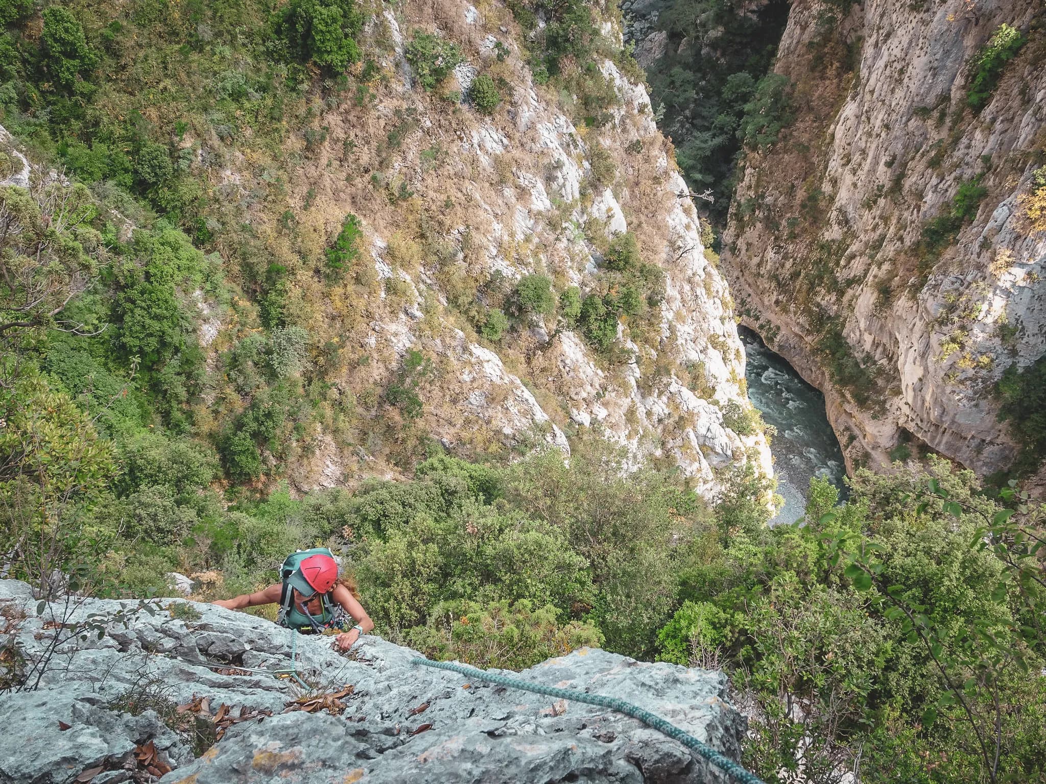Climbing in the Gorges du Verdon, overlooking lush green cliffs and a winding river.