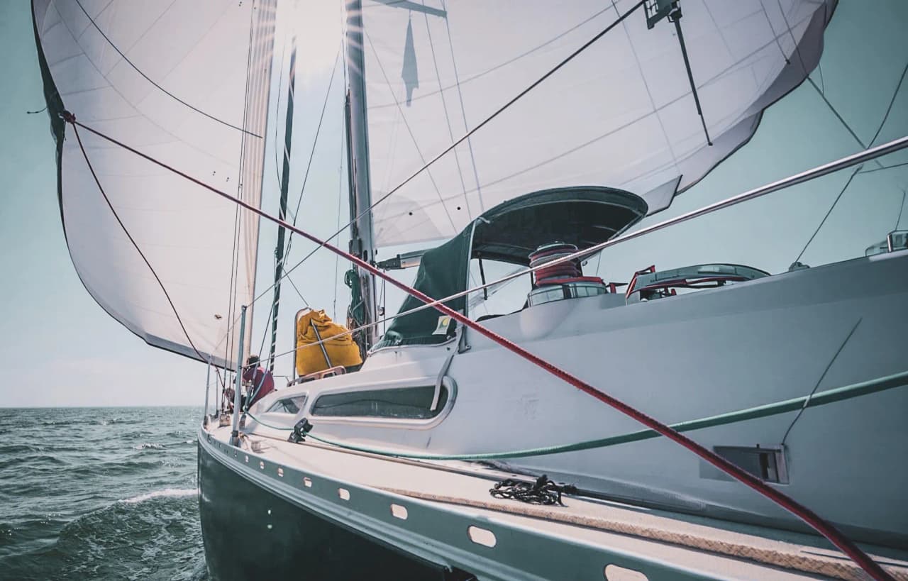 A majestic sailboat gliding through the water, sails billowing under a sunny sky. A maritime adventure in sight!