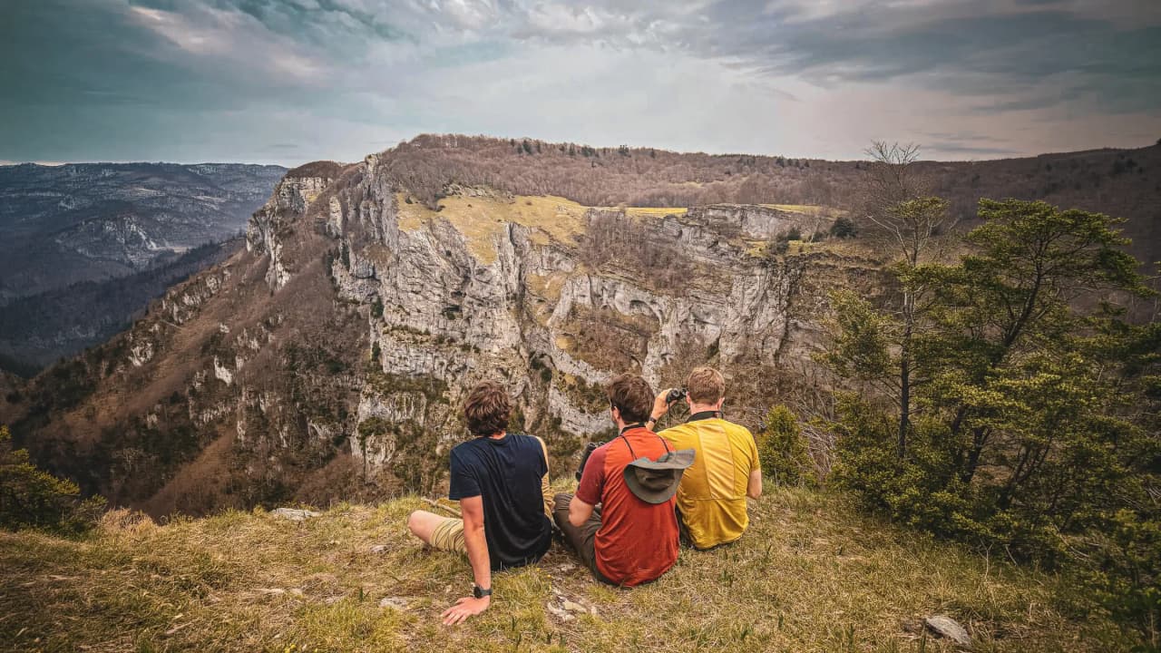 Drie avonturiers kijken uit over een majestueus berglandschap in de Vercors.