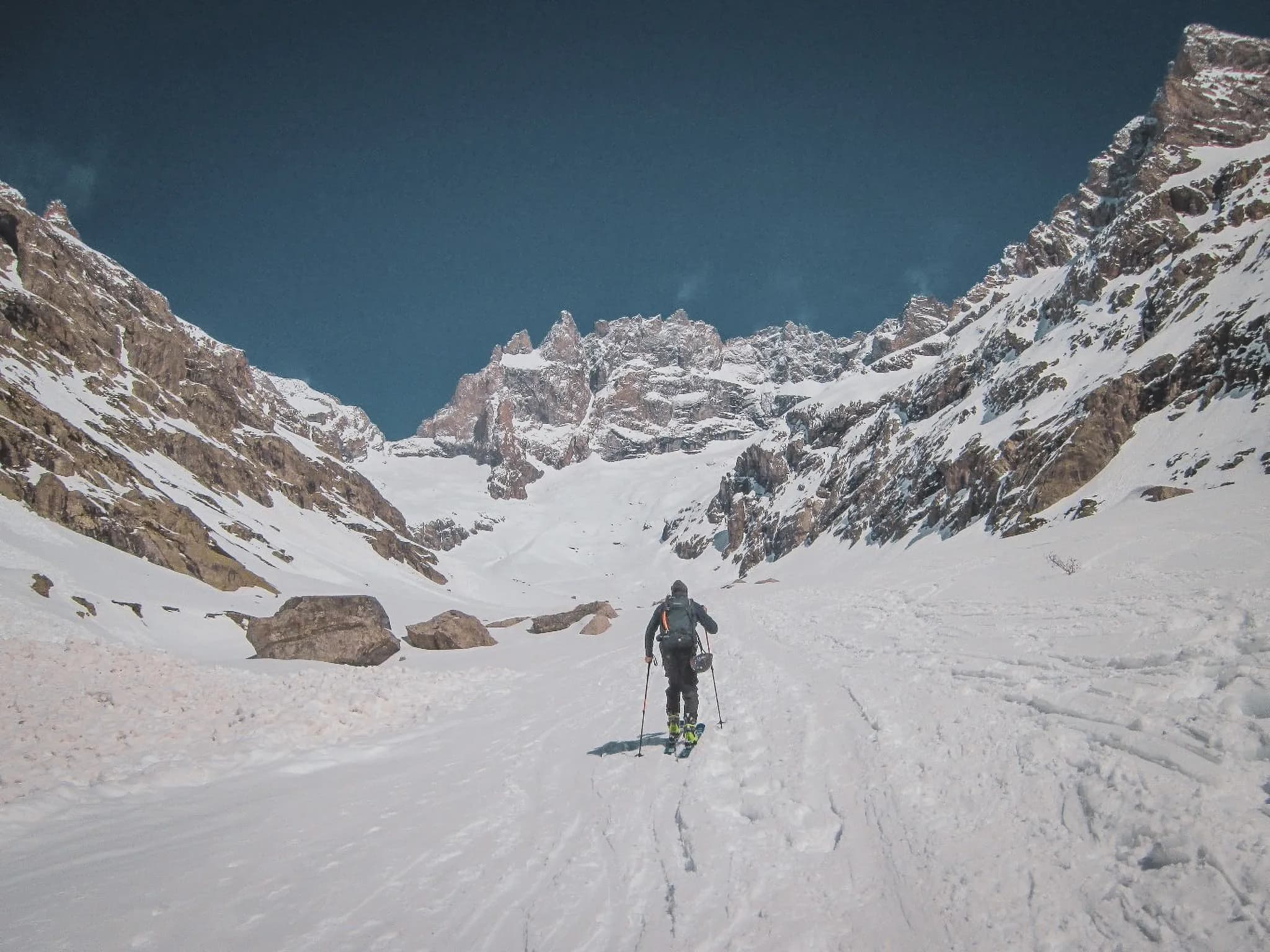 Een eenzame skiër baant zich een weg door een besneeuwde vallei, omringd door de majestueuze toppen van de Ecrins.