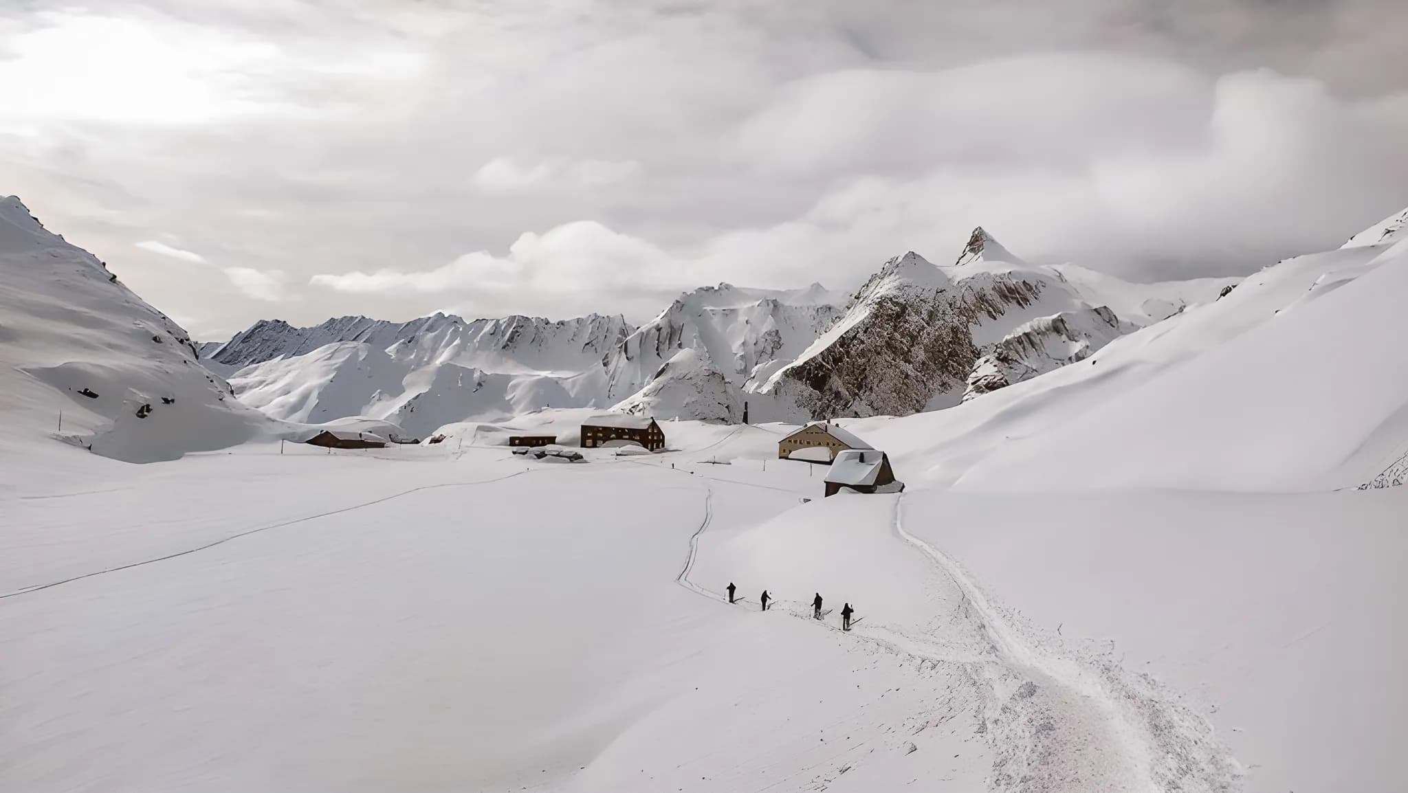 Een groep sneeuwschoenwandelaars doorkruist een besneeuwd landschap op de Grote Sint-Bernardpas.